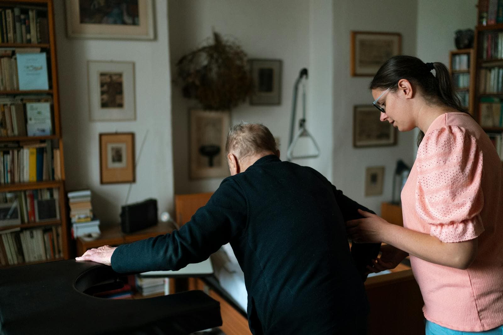 A young companion caregiver assists a senior man in his bright living room.