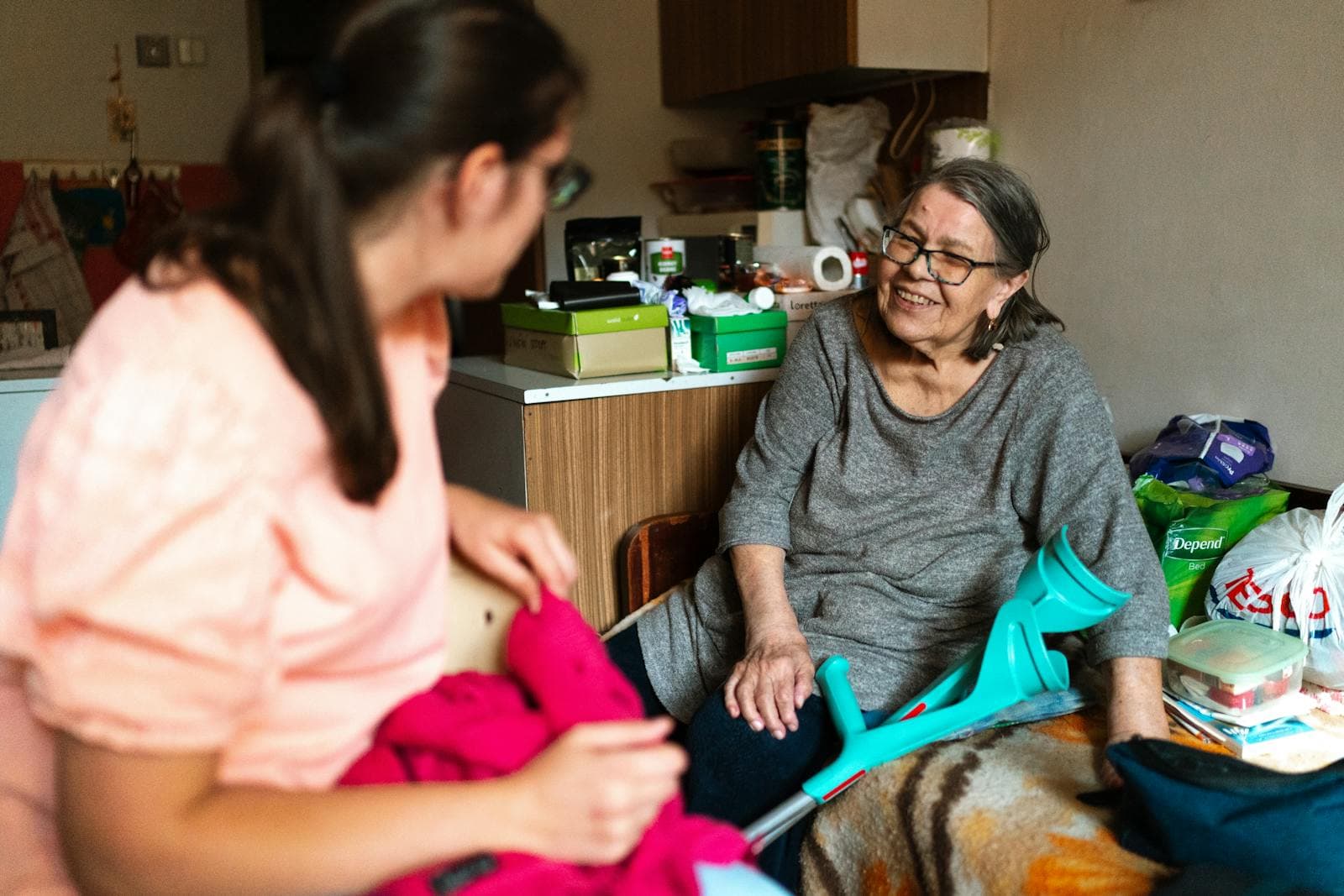A companion caregiver helps a senior woman steady herself with a crutch in her home — a moment that often signals it is time to consider in-home care.